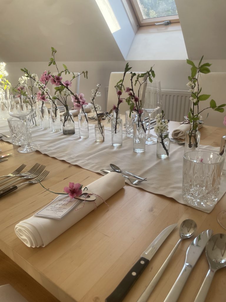 Gedeckter Tisch mit blühenden Zweigen