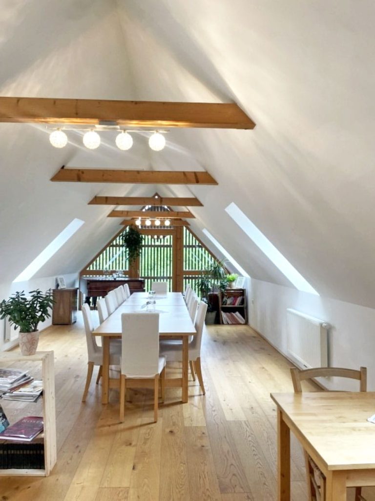 Dachgeschoß mit langem Tisch und weißen Stühlen
