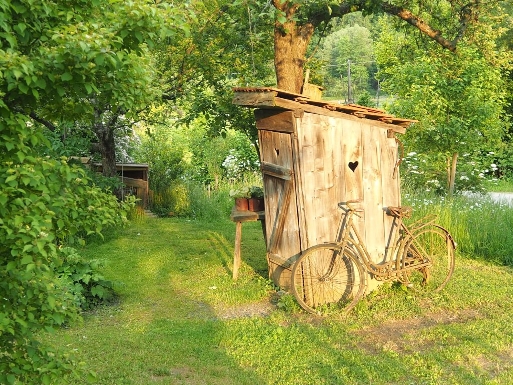 Toilettenhäuschen aus Holz, davor ein Fahrrad