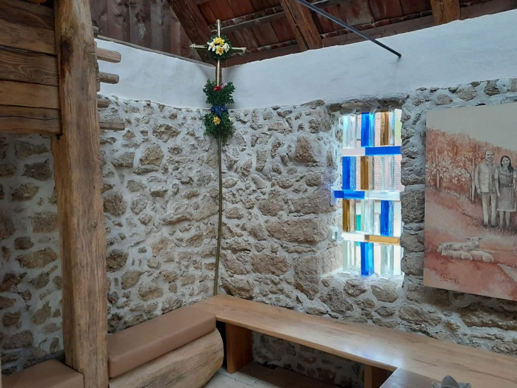 Steinmauer Kapelle mit Sitzbänken und buntem Fenster