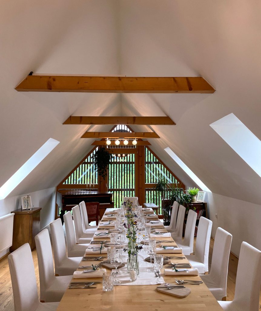 Ein elegantes Esszimmer-Set für ein „Tafeln“-Treffen in einem hellen Dachzimmer mit einem Klavier.